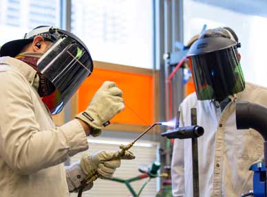 A student welding and another student watching